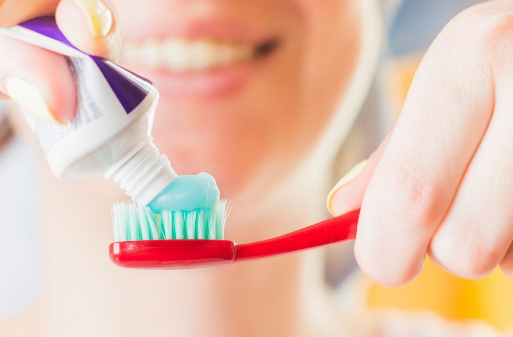 A woman is squeezing toothpaste with fluoride on her toothbrush.